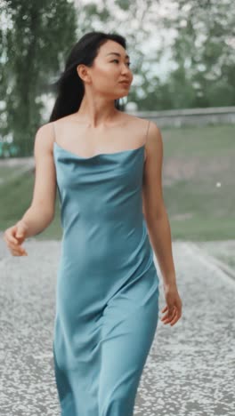 woman walking in a blue silk dress in a park