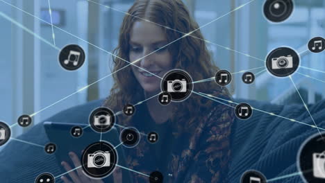 animation of network of connections with camera icons over caucasian woman with tablet