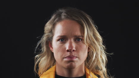 head and shoulders studio shot of unhappy woman looking at camera with sad expression in slow motion