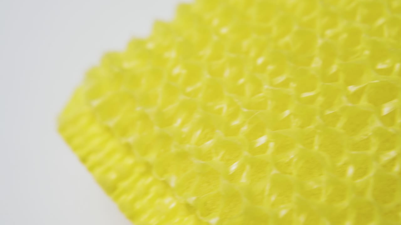 loofah amarillo para la limpieza de utensilios en superficie blanca