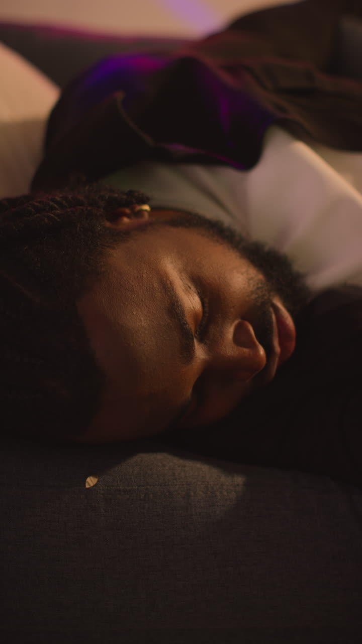 video vertical de un hombre confundido despertando sentado en el sofá después de beber alcohol en una fiesta de casa sufriendo de resaca 2