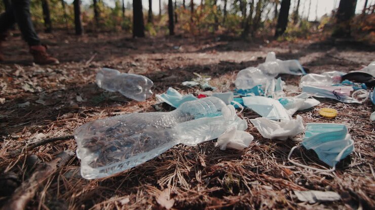 Un uomo cammina nel bosco oltre una discarica di rifiuti domestici