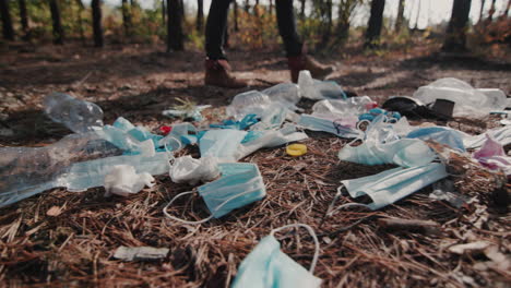 a man walks through the woods past a landfill made of household rubbish