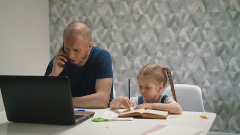 father-talks-on-phone-trying-to-work-daughter-does-homework