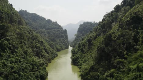 a tranquil river winds through dense green mountains in the lush jungles of vietnam