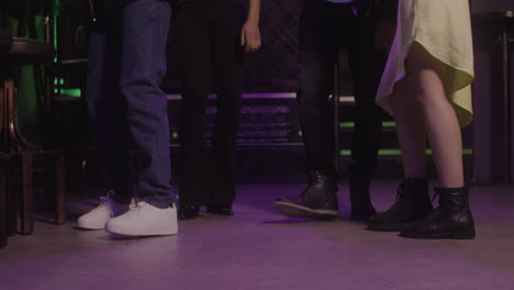 close up of legs of four unrecognizable people dancing at disco club