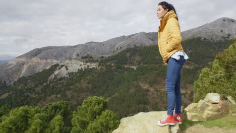 Woman-in-yellow-coat-near-mountain-valley