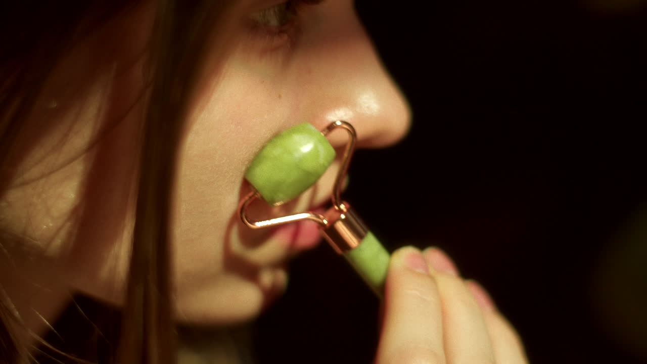 얼굴 마사지를 위해 재드 롤러를 사용하는 여성