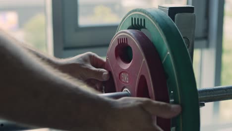 man loading weight plates on a barbell in a gym