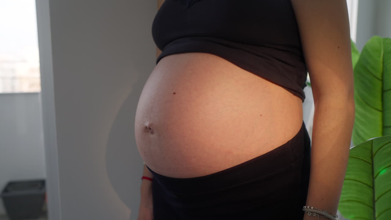 Pregnant Woman's Belly Illuminated by Moving Colorful Lights