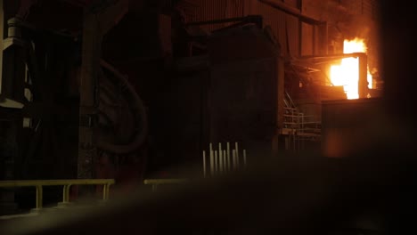 nighttime shot of industrial furnace at steel mill, fiery glow illuminating the dark scene