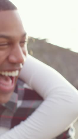 four adult friends laughing piggybacking in the sun