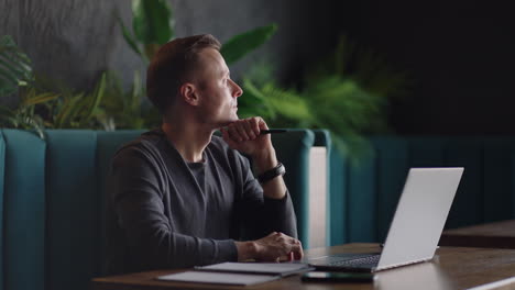 Thoughtful-serious-young-man-student-writer-sit-at-home-office-desk-with-laptop-thinking-of-inspiration-search-problem-solution-ideas-lost-in-thoughts-concept-dreaming-looking-away