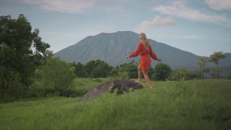 carefree woman running towards boulder and taking in awe-inspiring view of mount agung, savana tianyar