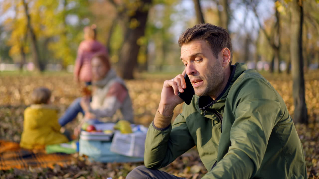 Man talking on phone with family in park during autumn