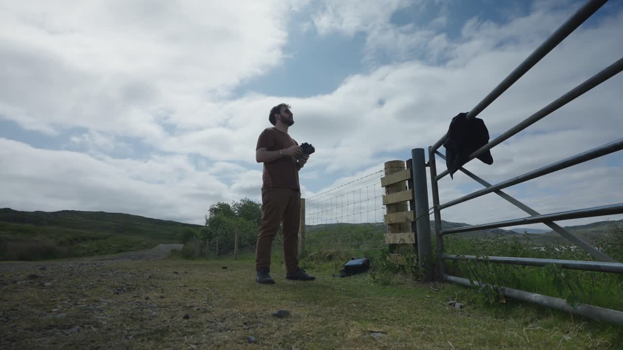 남성 드론 조종사는 시골 지역에 손으로 작은 드론을 착륙시켜 잠그고 있습니다.