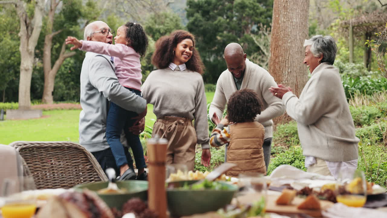 A multigenerational family celebrates together outdoors, enjoying a meal and each other's company.