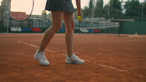 for tennis training a girl stands on the central service line. bangs the ball on the court. serve. the camera moves from the ground to medium close-up