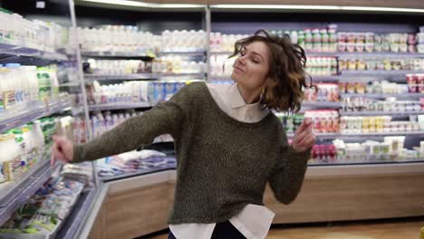 Mujer-Joven-Bailando-A-Través-De-Los-Pasillos-De-La-Tienda-De-Comestibles.-Mujer-Emocionada-Divirtiéndose,-Bailando-Supermercado.-Camara-Lenta