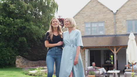 senior mother with adult daughter walking and talking in garden together