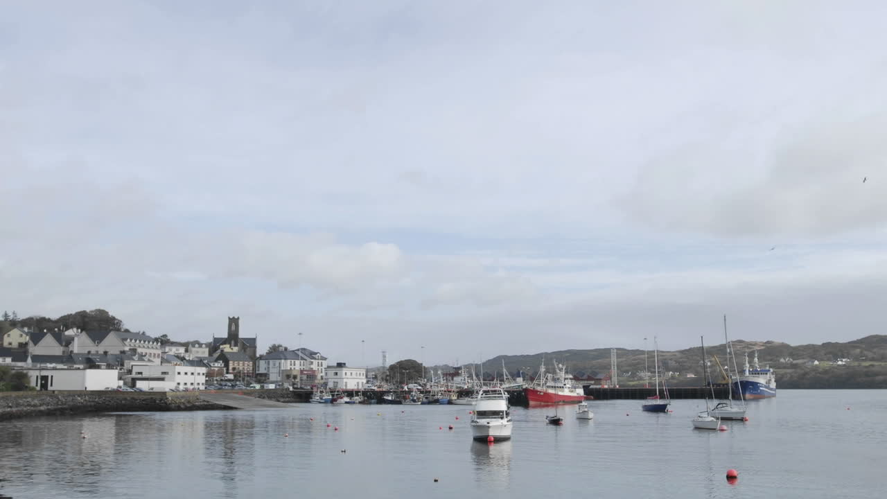 lapso de tiempo de nubes y barcos que soplan en el viento en el puerto de killybeg irlanda