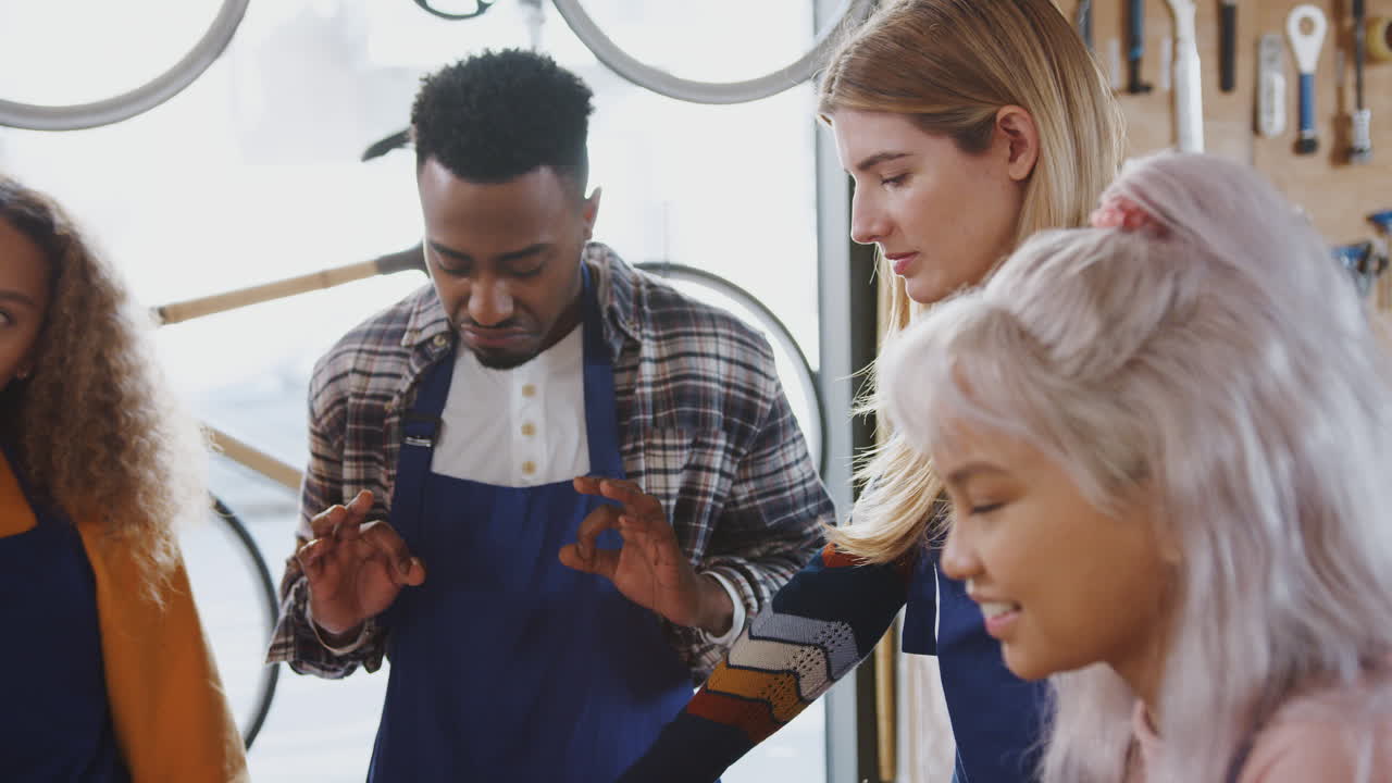 equipo multicultural de aprendices en el taller aprenden a ensamblar un marco de bicicleta construido a mano juntos