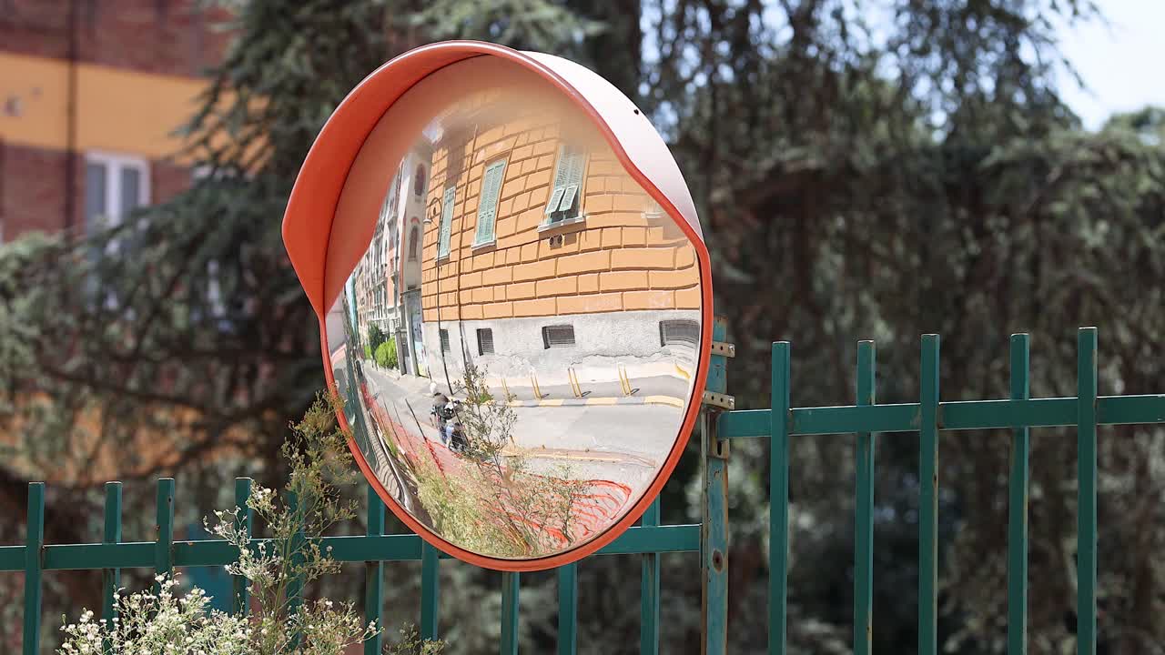 дорожное зеркало, отражающее здание и улицу