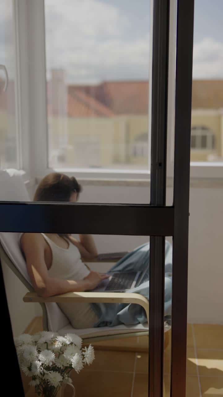 mujer trabajando en una computadora portátil en el balcón