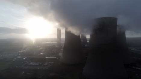 Aerial-view-towards-UK-power-station-cooling-towers-smoke-steam-emissions-at-sunrise-closeup