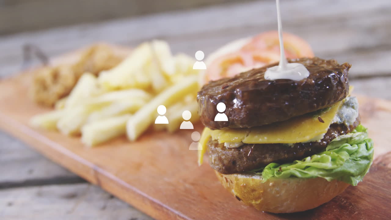 Burger with cheese and lettuce on wooden board, fries in background, animation