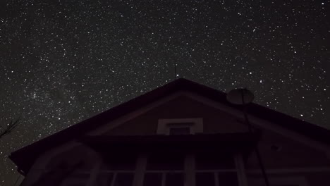 Cielo-Nocturno-Estrellado-Giratorio-Sobre-Una-Casa-Con-Luces-Parpadeantes