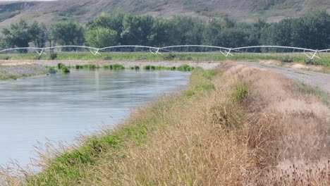 irrigation canal and pivot bring water to crops in arid prairie valley