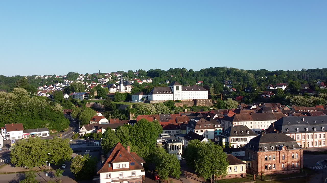 Aerial drone footage of Blieskastel, a historic town in Saarland, Germany, captured on a clear summer day with traditional houses, greenery, and landmarks