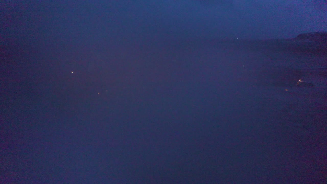 A peaceful drone shot glides through morning mist, slowly revealing an Icelandic church surrounded by fog-kissed fields and distant snow-covered hills.