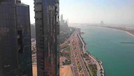 toma aérea ascendente de una gran autopista en abu dhabi cerca de los rascacielos