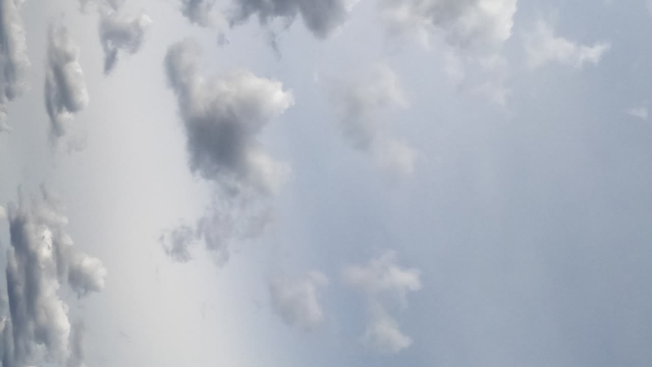Grey cumulus clouds flying at the horizon. Dramatic rainy sky from low angle view. Timelapse. Vertical screen.