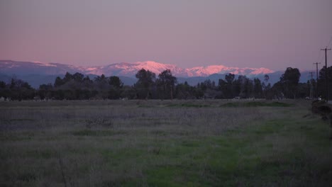 un cielo pastel sobre las montañas de sierra nevada con líneas eléctricas y árboles, en primer plano en clovis, ca, ee.uu.