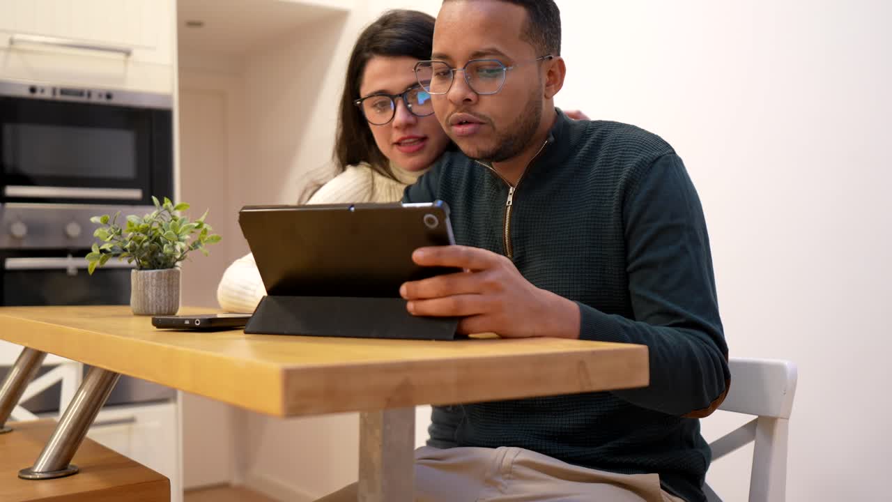 Happy Couple Using Laptop and Tablet in Modern Kitchen