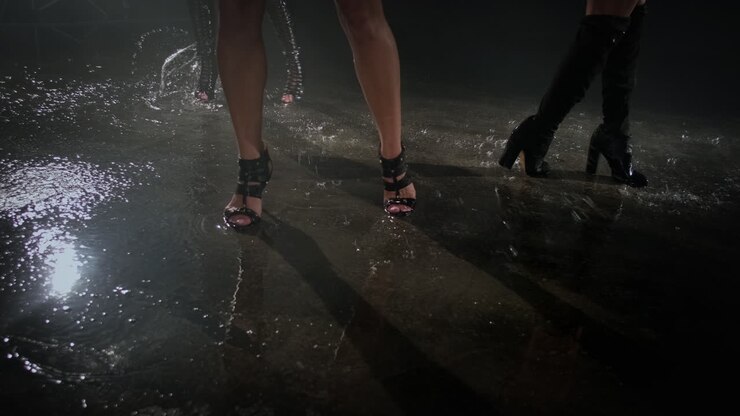 Donne con i tacchi che camminano sotto la pioggia