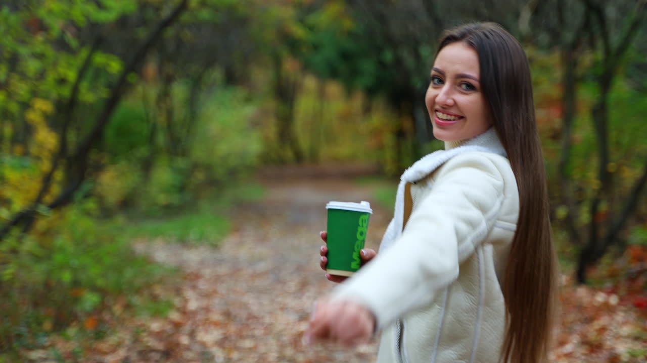 Donna che cammina in un bosco autunnale con caffè
