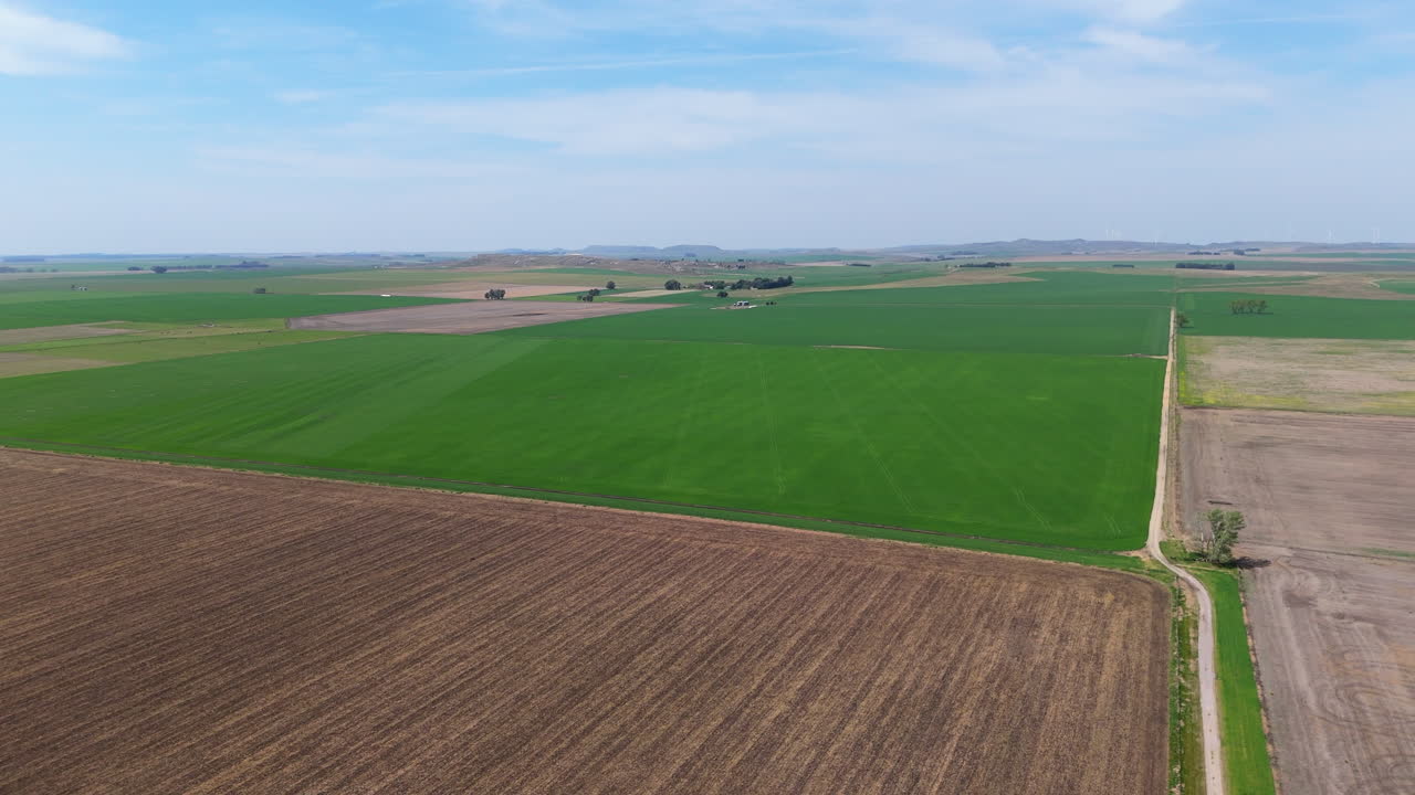 Aerial View of Agricultural Fields with Green and Brown Patches in Countryside, cloudy blue sky, slow motion, copy space