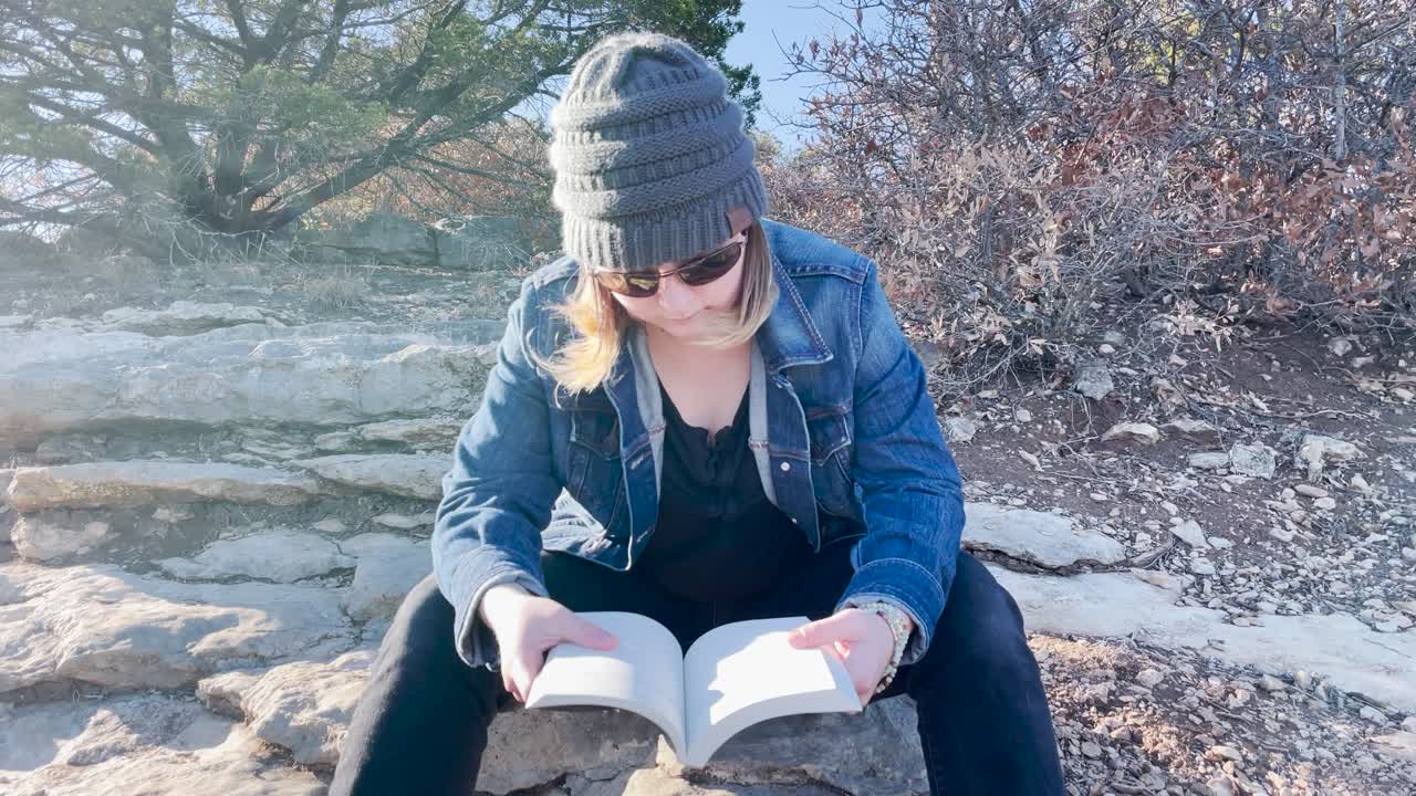 girl flips through pages of a book outside in nature