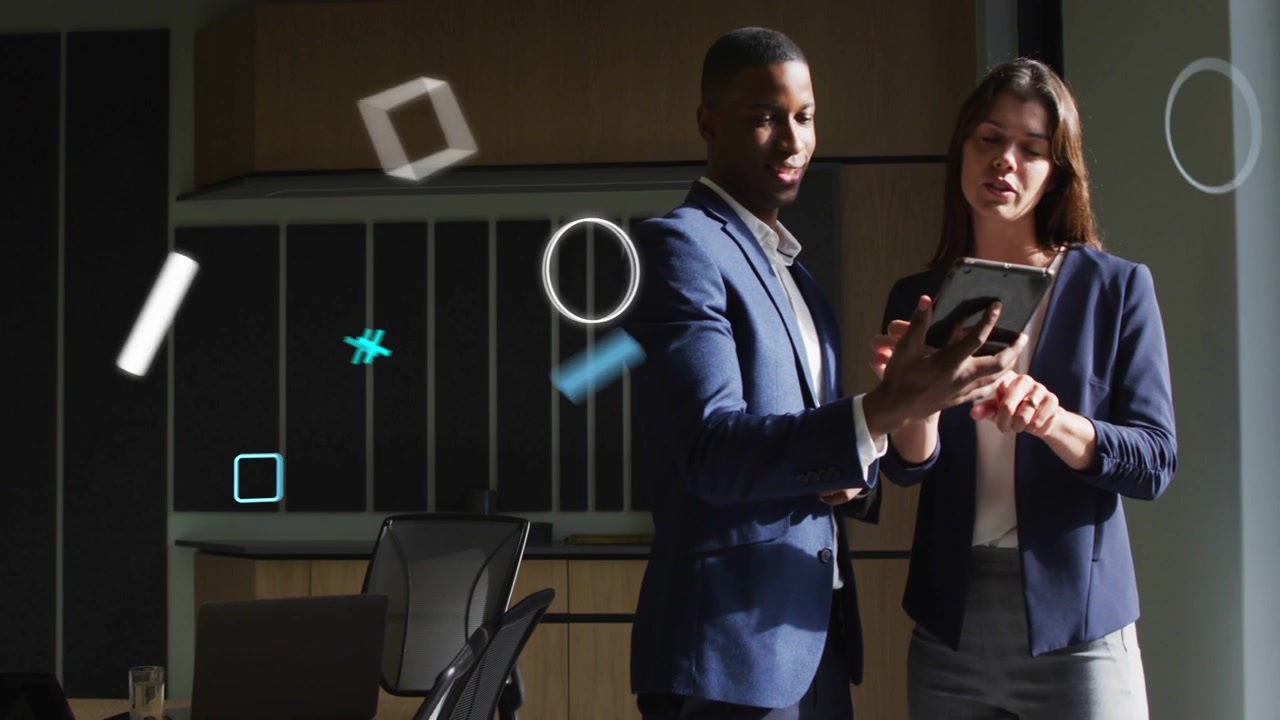 Man showing tablet and woman tapping it in business room floating graphics guiding data reviewing