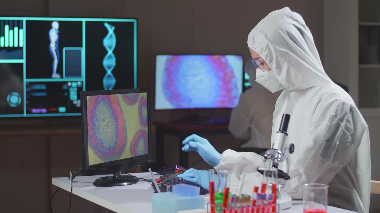 Asian Doctor In Protective Suit Working On Computer In A Modern Lab. Laboratory Assistant Workplace. The Concept Of Science And Medicine