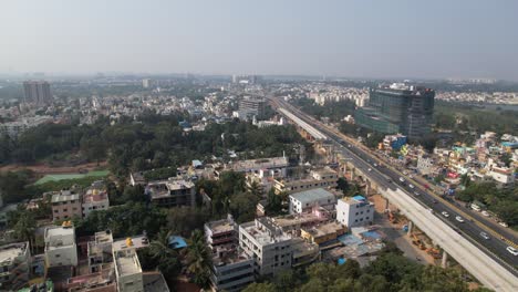 a service road, quickly moving cars, and residential and commercial buildings on an expanding indian highway are all depicted in dramatic aerial footage