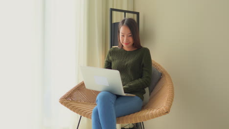 Attractive-Asian-Female-In-Family-Home-Using-Laptop-Work-Online-Work-and-Instant-Communication,-Static-Shot-With-Copy-Space