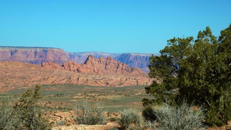 tilt up extreme wide landscape shot revealing a dry desert landscape with colorful mountains and plateaus covered in sage brush on a hike in arizona, usa during a warm sunny spring morning