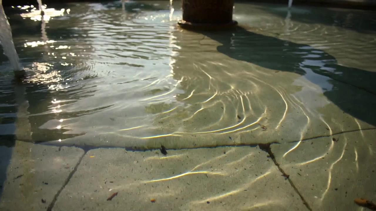 Jet entry creating ripples and moving caustic light across courtyard basin, column shadow