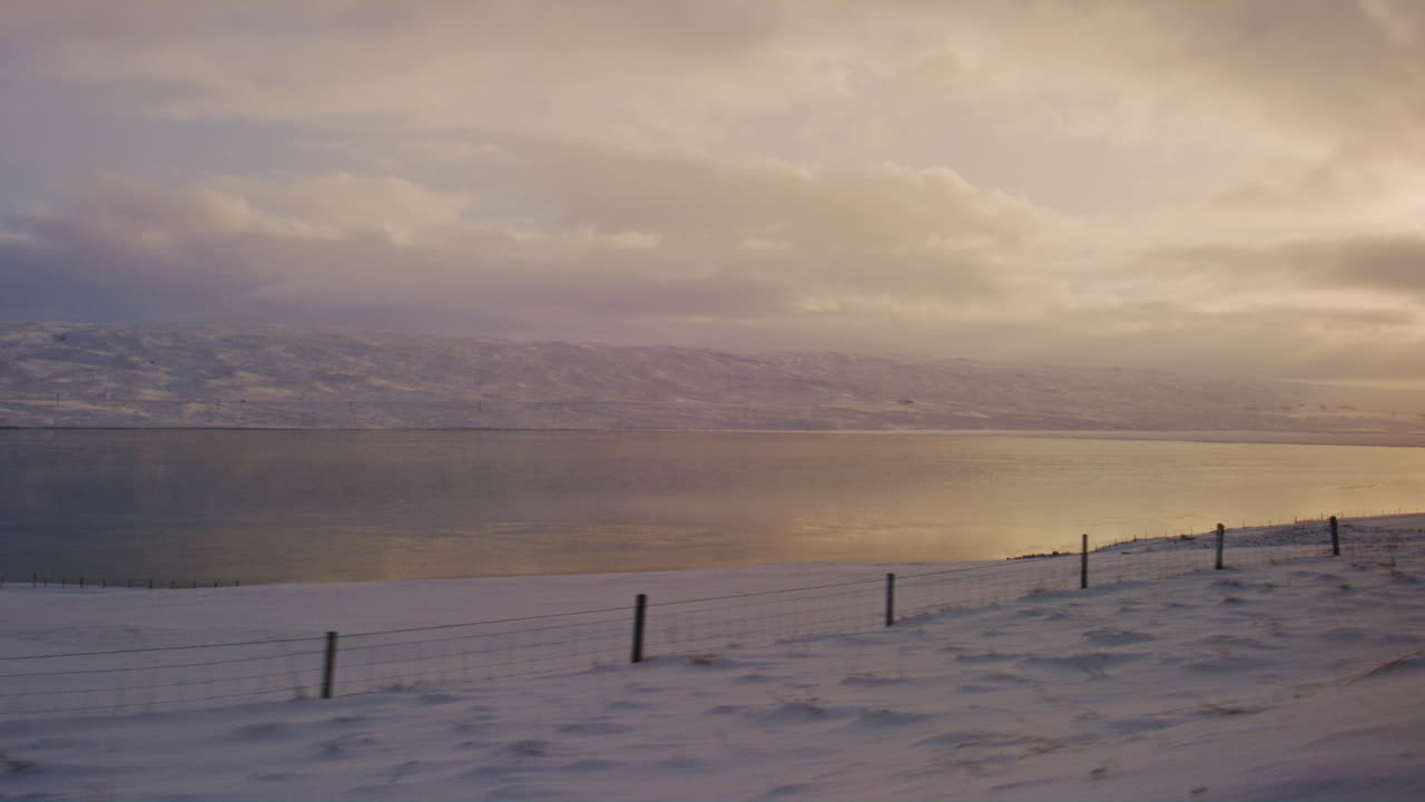 Icelandic tundra glowing in sunrise light, frozen plains creating a serene winter leading to soft sky yellow reflections in water