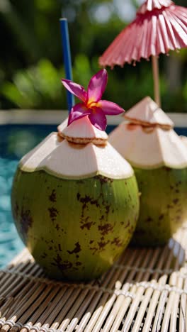 close-up of tropical coconuts with flowers and straws by a poolside, shot at a low angle, perfect